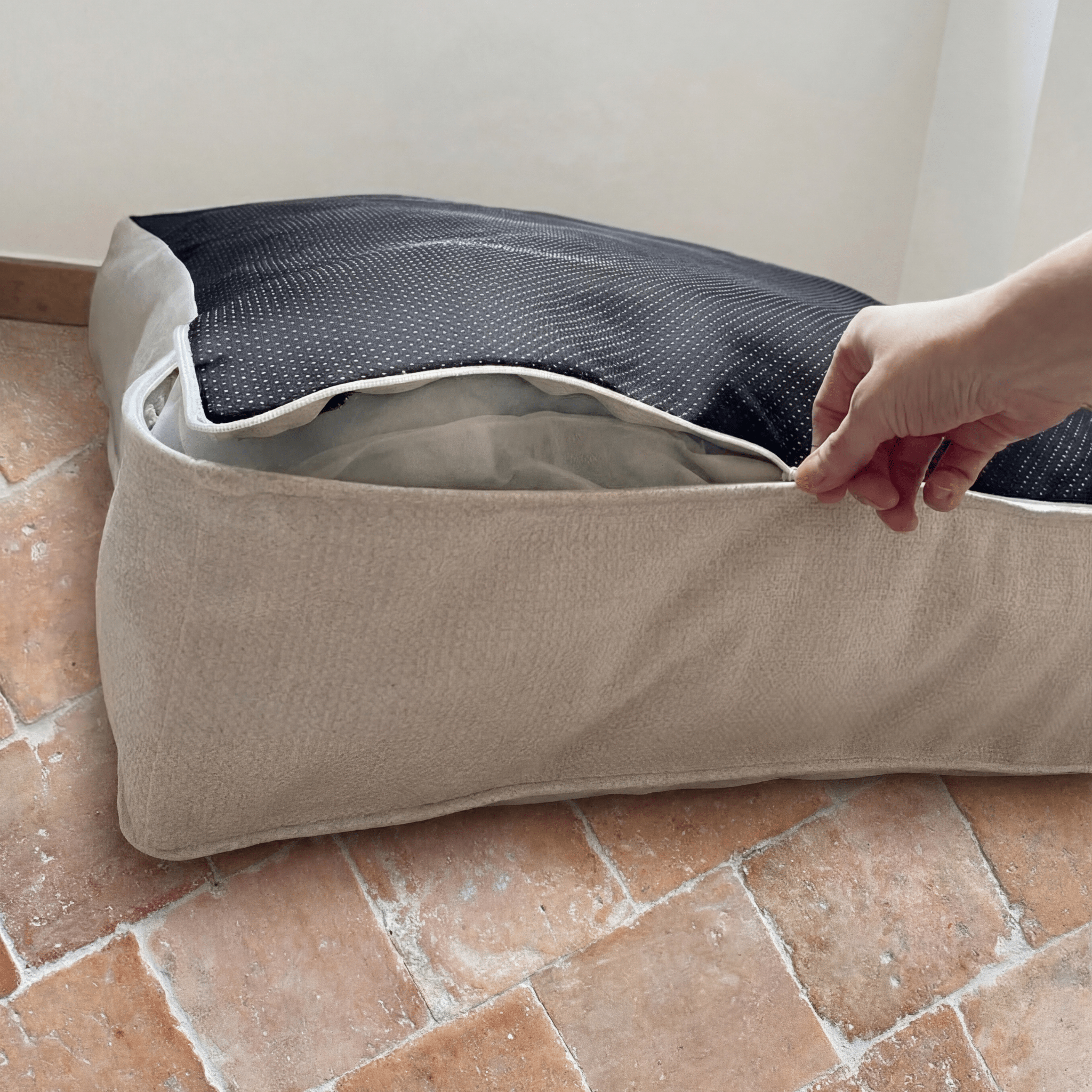 détails couture du panier lit nesto, avec une main qui ouvre la fermeture éclair du panier déhoussable