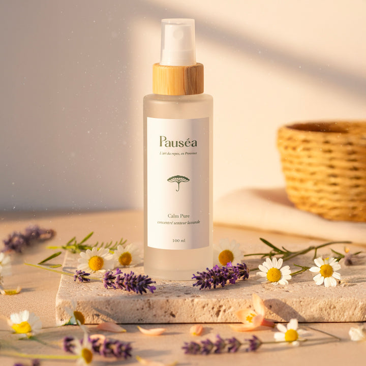 Spray naturel Calm Pure Pauséa posé sur pierre beige avec lavande et camomille, ambiance douce provençale au coucher du soleil.