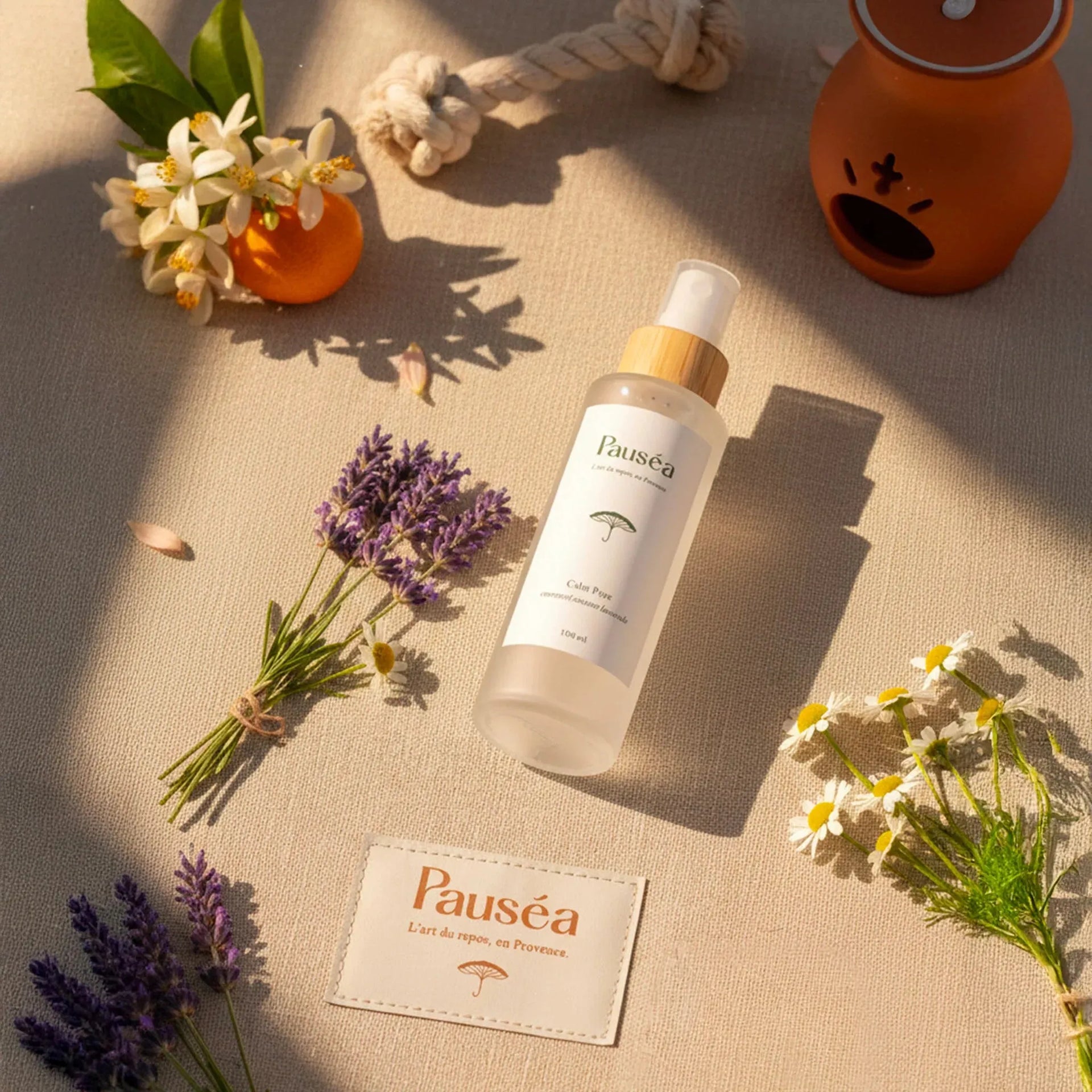 Spray Pauséa Calm Pure sur toile beige, entouré de lavande, camomille, fleurs d’oranger et corde artisanale provençale.